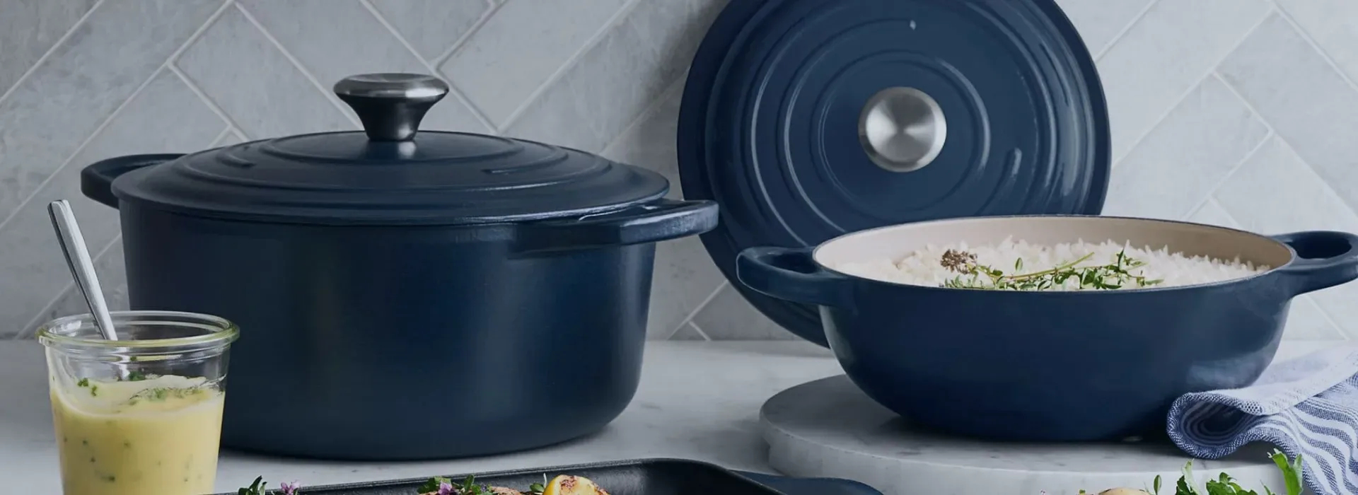 Navy enamel cookware on a marble counter